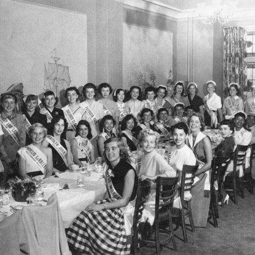 A crowd of people, many children, gathered outdoors as if for a ceremony or event, with a few adults watching in the background.