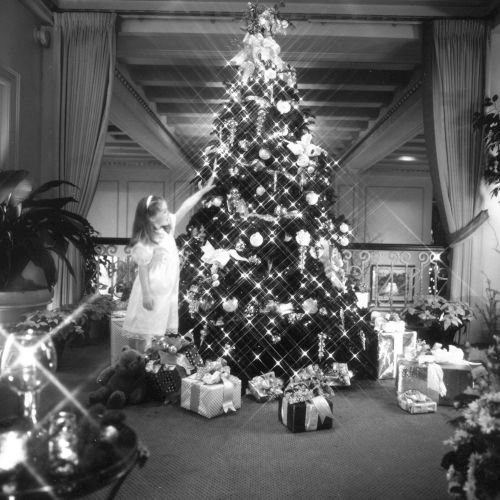 A cozy vintage living room with a large Christmas tree, wrapped gifts, and festive garlands.