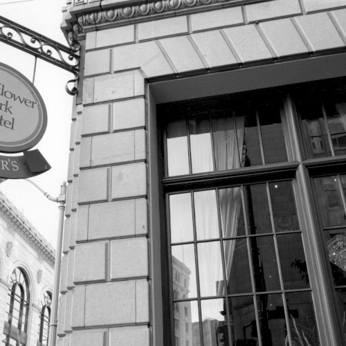 An old clock tower and stone building with a barred window, captured in black and white.