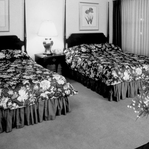 A large group of people sits in a long hall or church, facing forward, with many windows and arches along the sides.