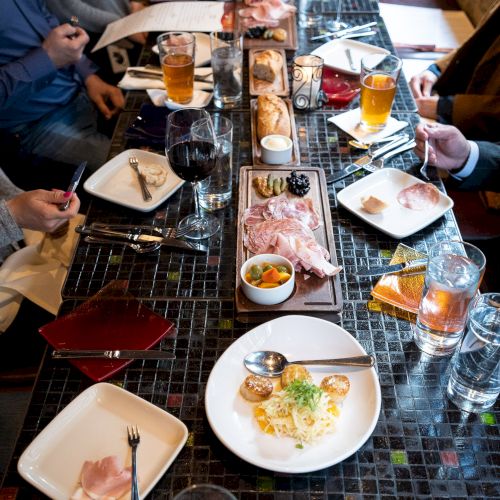 A long table with plates of appetizers and drinks, people dining together in a casual restaurant setting.